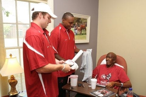 Alabama Crimson Tide players Greg McElroy and Luther Davis visit with Herman Hurst.